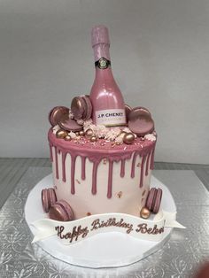 a birthday cake with a bottle of champagne and chocolates on top is decorated in pink icing