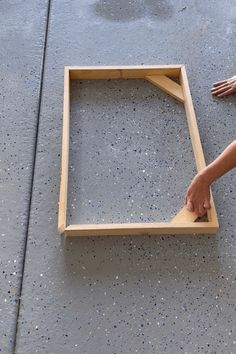 someone is making a frame out of plywood and cement on the ground with their hands