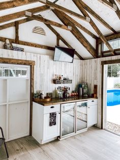 a kitchen with white cabinets and wood floors next to a swimming pool in the background