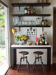 two stools sit in front of a bar with bottles and glasses on top of it