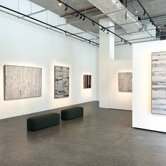 an empty room with three paintings on the wall and two benches in front of them