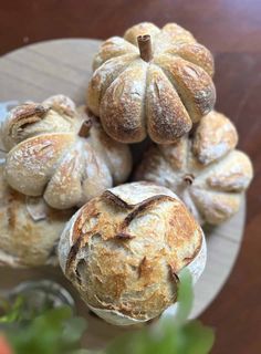 several round breads on a plate with some leaves in the foreground and other food items to the side