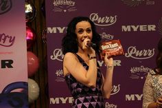 a woman holding a candy bar in front of her face while standing next to another woman