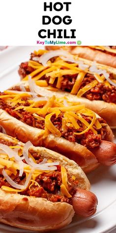 three hot dogs with cheese and chili on them sitting on top of a white plate