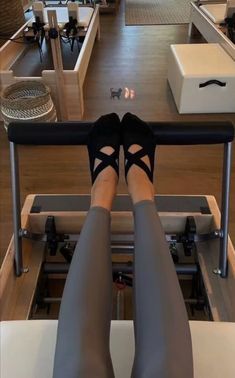 the legs of a woman who is sitting on a machine in a room with lots of furniture