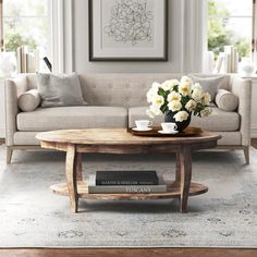 a living room filled with furniture and flowers on top of a coffee table in front of a window