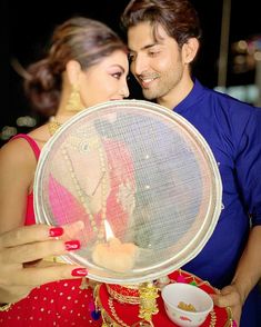 a man and woman standing next to each other holding a plate with a candle in it