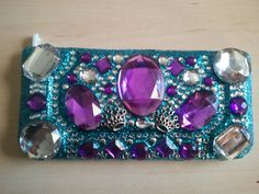 a purple and blue beaded purse sitting on top of a wooden table