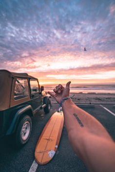 a man is holding his hand up to the sky while standing next to a jeep