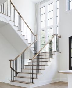 a white staircase with wooden handrails in a living room next to a window