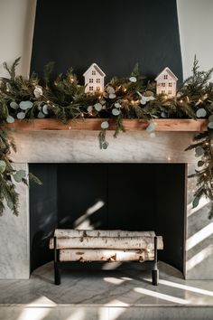 the fireplace is decorated with greenery and houses