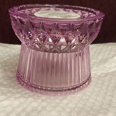 a pink glass candle holder sitting on top of a table