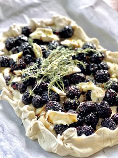 an uncooked pastry with blueberries and herbs on top