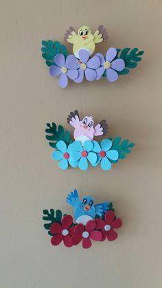 three paper birds hanging on the wall with flowers and leaves in it's beaks