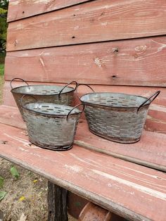 two metal buckets sitting on top of a wooden bench