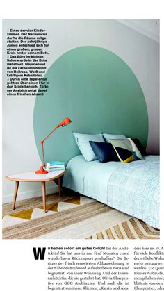 a bed with blue sheets and pillows in a bedroom next to a green circle painted on the wall