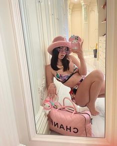 a woman is taking a selfie in the mirror with her pink purse and hello kitty hat