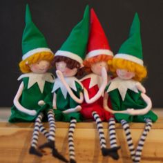 three elfs sitting on top of a wooden table next to each other with their legs crossed