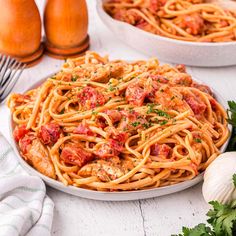 a plate of spaghetti with tomato sauce and parmesan cheese on the side next to garlic