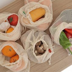 five bags filled with vegetables sitting on top of a wooden table next to each other