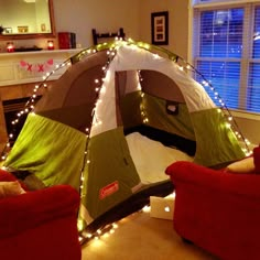 a tent that is sitting in the middle of a living room with lights on it