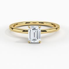 a yellow gold ring with an emerald stone in the center and a thin band around it