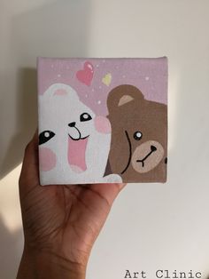 a hand holding up a small painting with two bears on it