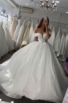 a woman in a wedding dress is taking a selfie with her cell phone while looking at the dresses on display