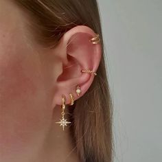 a close up of a person's ear wearing gold earrings with stars on them