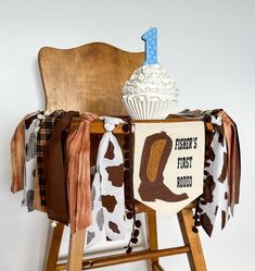 a wooden chair with a cow print table cloth and cupcake on it's back