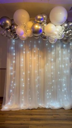 the balloons are hanging from the ceiling above the curtain in front of the party table