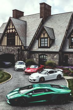 four different colored sports cars parked in front of a house