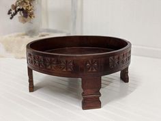 a wooden bowl sitting on top of a table next to a vase with flowers in it