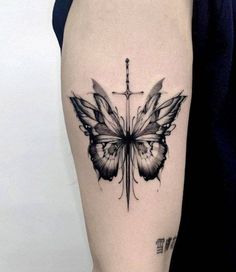 a black and white butterfly tattoo on the right thigh, with cross in the background