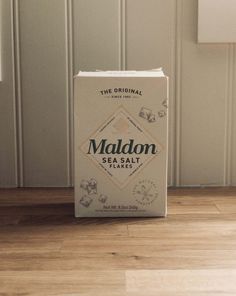 a box of maldon sea salt sitting on top of a hard wood floor next to a wall