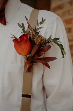 a man wearing a white shirt and suspenders with flowers on his lapel