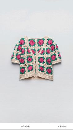 a crocheted sweater with pink flowers on the front and green, red, and white design