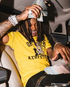 a man with dreadlocks sitting in the back seat of a car holding money