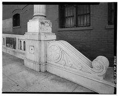 a black and white photo of an old building with a stone fence next to it