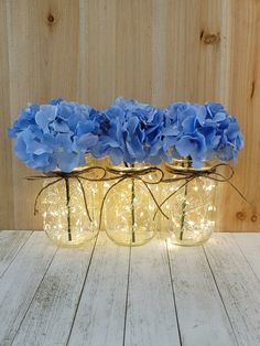 three mason jar vases filled with blue flowers