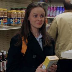 a woman is holding a box in a grocery store