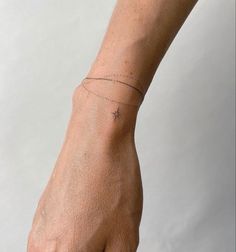 a person's hand with a tiny cross tattoo on the left side of their wrist