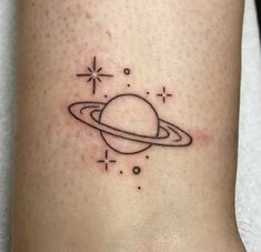 a small saturn tattoo on the ankle, with stars and planets in the sky above it