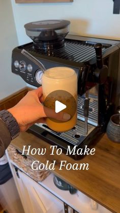 a person is holding a beer in front of an espresso machine with the words how to make cold foam