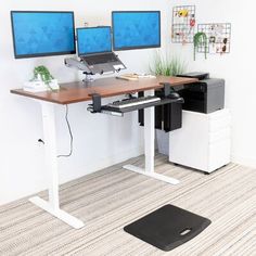 two computer monitors sitting on top of a wooden desk