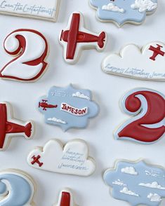 decorated cookies with red and blue icing are arranged on a white surface, including two airplanes