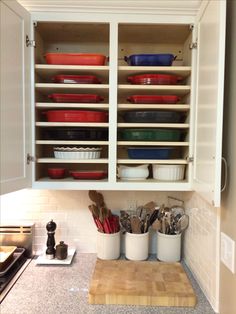 a kitchen cabinet filled with bowls and utensils