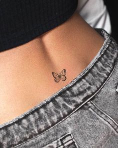 a woman's stomach with a small butterfly tattoo on her lower back ribcage