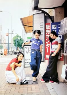 three people standing next to each other on a sidewalk