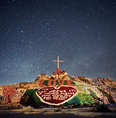 a cross on top of a hill with the word love written on it and stars in the sky above